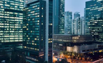 Skyscrapers dominate the foreground of a bustling city at night, with tall buildings and busy streets at The Puli Hotel and Spa