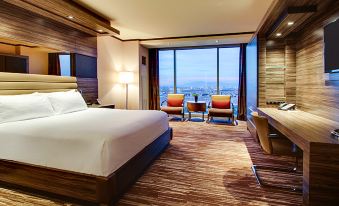 a modern hotel room with a large bed , two chairs , and a view of the city through a large window at M Resort Spa & Casino