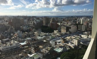 a cityscape with a mix of tall buildings and smaller ones under a cloudy blue sky at Hyatt Regency Naha, Okinawa