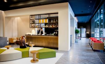 a modern bar area with a wooden counter and green seating , where two people are sitting at Glam Milano