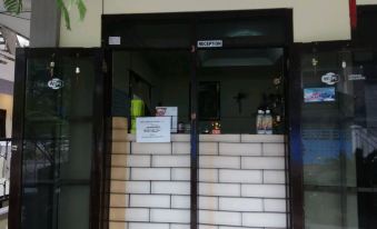 a white brick building with a black door and glass windows , as well as a sign on the door at Adel Guest House