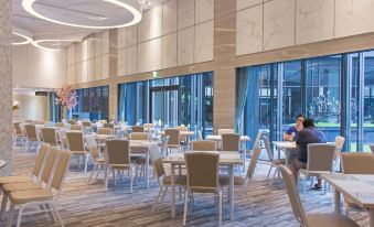 a large , modern dining room with multiple tables and chairs arranged for a group of people to enjoy a meal together at Platinum Hotel