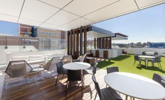 a patio area with several chairs and tables arranged for outdoor dining , providing a pleasant environment for socializing and socializing at The Milton Brisbane