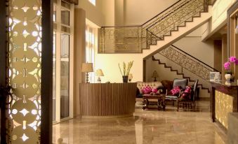 a luxurious hotel lobby with a staircase leading to the second floor , where a reception desk and several chairs at Sapphire Sky Hotel & Conference