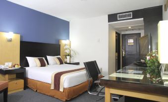 a modern hotel room with a large bed , desk , and sliding glass door to the bedroom at Jayakarta Hotel Jakarta