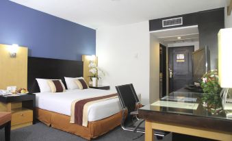 a hotel room with a king - sized bed , a desk , and a chair , as well as a door leading to another room at Jayakarta Hotel Jakarta