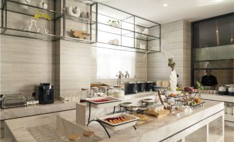 a modern kitchen with a dining table , a buffet of food , and a counter with various appliances at Atour Hotel