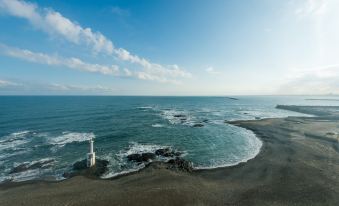 aerial view of a rocky shoreline near the ocean , with a lighthouse in the distance at OARAI HOTEL