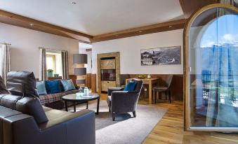 a cozy living room with wooden floors , a fireplace , and comfortable furniture , including a couch , chairs , and a coffee table at Schlosshotel Fiss
