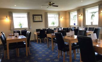 a dining room with several tables and chairs arranged for a group of people to enjoy a meal together at The Anchorage Hotel