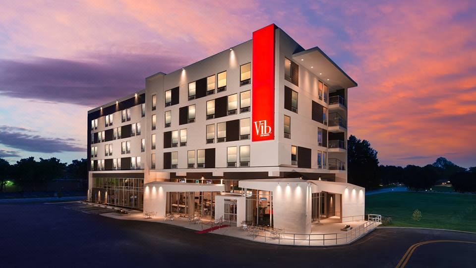 "a modern hotel with a red sign that says "" vib "" is shown against a pink and purple sky" at Best Western Plus Executive Residency Austin