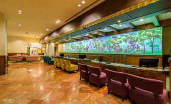a large aquarium is visible behind a counter with colorful chairs in front of it at Oriental Hotel Tokyo Bay