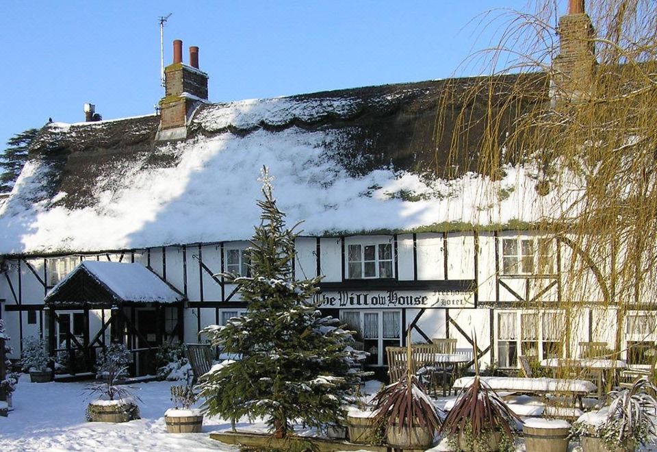 a traditional english pub with snow on the roof and a christmas tree in front of it at The Willow House