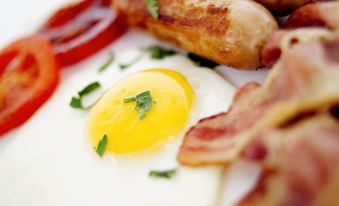 a white plate with a sunny side up egg , bacon , and sausage on top of white rice at Cameron Thermal Motel