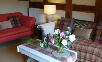 a cozy living room with a red chair , a red couch , and a potted plant on a coffee table at Moor Court Farm