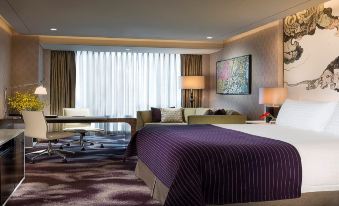 A spacious room is furnished with a bed, desk, and chair in the center, resembling an oriental style at Four Seasons Hotel Shenzhen