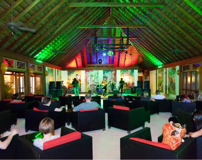 a group of people gathered in a room , watching a band play on stage and engaged in the activity at Vilamendhoo Island Resort & Spa