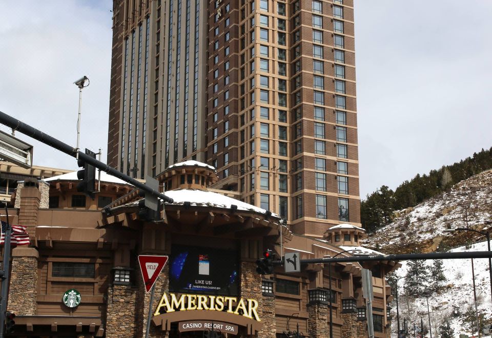 a tall building with a large sign on the side , surrounded by snow - covered ground and trees at Ameristar Casino Black Hawk