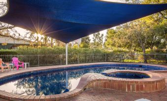 a blue tarp covering a swimming pool , providing shade and protection from the sun , while surrounded by greenery at Big4 Borderland Wodonga