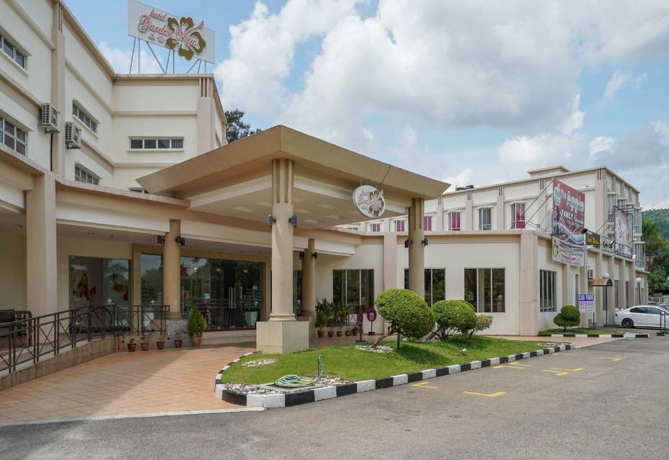 a large building with a white exterior and a flag in the top left corner at Garden View Hotel