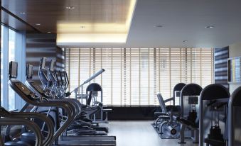 adjacent gym with large windows and a variety of exercise equipment mounted on the walls at Courtyard by Marriott Shanghai Central