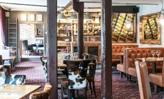 a dining room with a table surrounded by chairs , and a wine rack on the wall at The White Hart