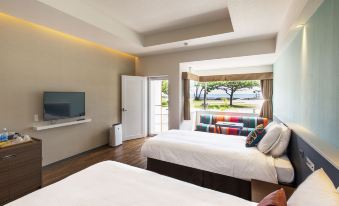 a room with two beds , one on each side of the room , and a television mounted on the wall at Sunset Beach Hotel