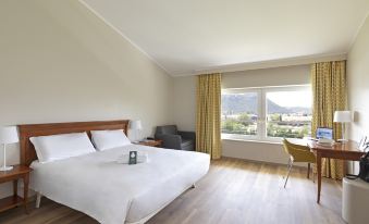 a spacious hotel room with a large bed , a chair , and a window overlooking the city at B&B Hotel Affi - Lago di Garda