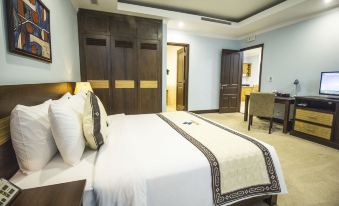 a large bed with a white and black blanket is in a room with wooden furniture at Golf Phu My Hotel