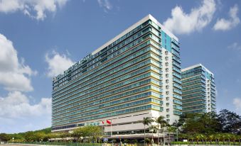 A large building with numerous windows on the sides and one in the front stands against a backdrop of blue sky at Regal Riverside Hotel