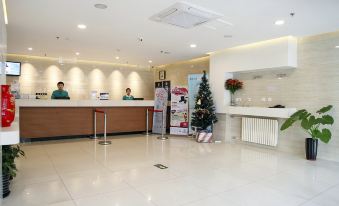 The reception area has people at the front desk and an entryway to another room at Jinjiang Inn (Beijing Anzhenli)