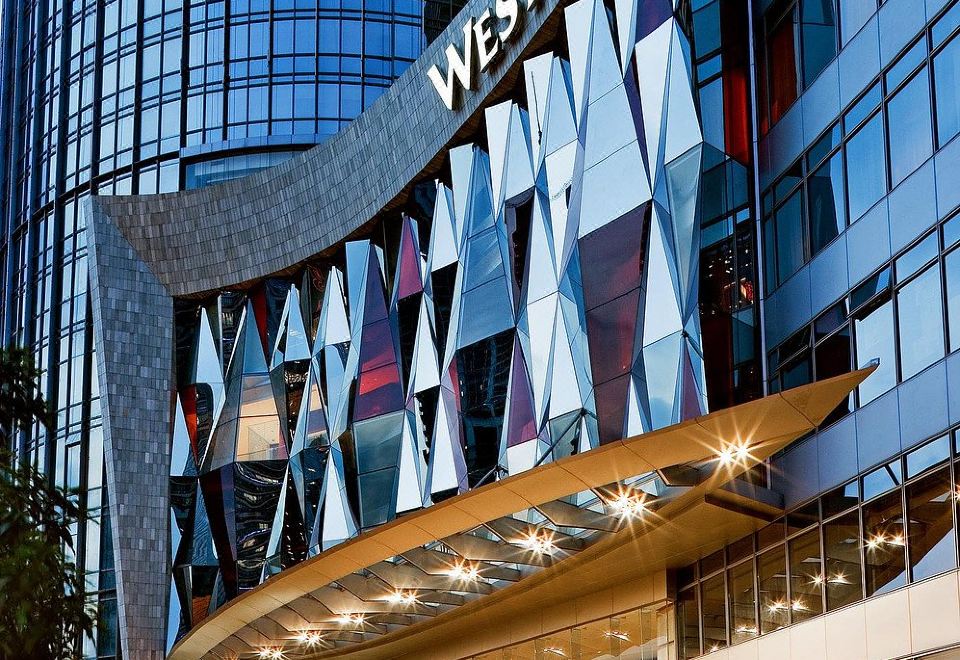 A large building with an illuminated sign on its side, along with other nearby buildings, has a front entrance at the Westin Guangzhou