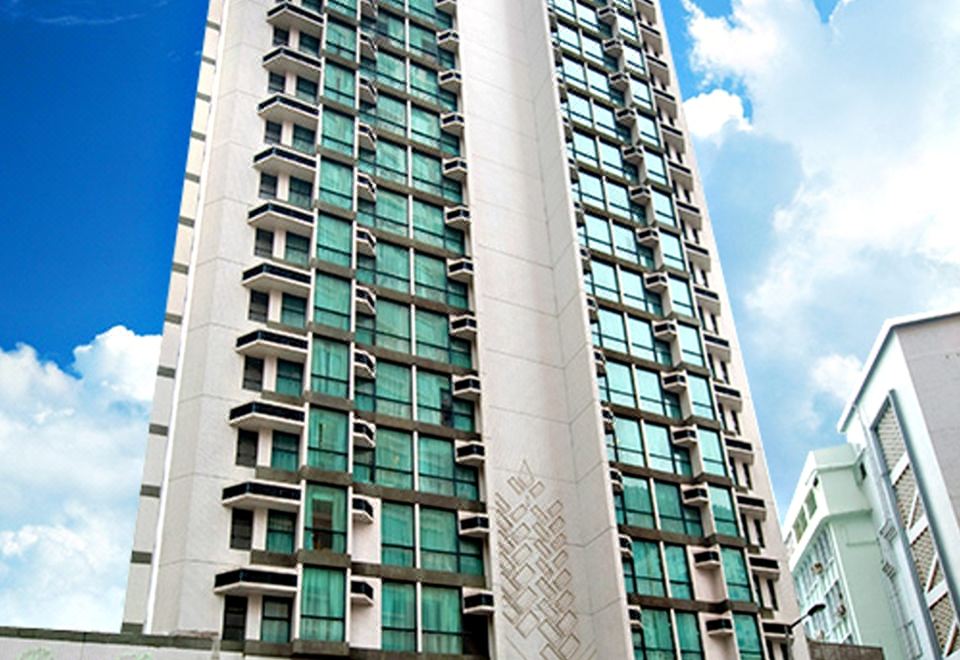 A tall apartment building stands in the city against an overcast sky at Bishop Lei International House