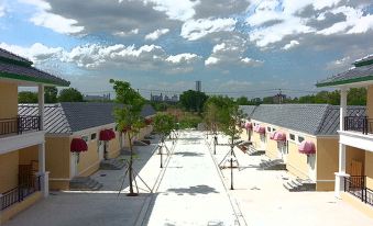 a paved walkway leading up to a row of small houses , with a cloudy sky overhead at Pudis Ville