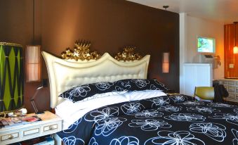 a bed with a floral comforter and gold accents is situated next to a wall at Motel Lodge