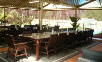 an outdoor dining area with a large wooden table surrounded by chairs , creating an inviting atmosphere at Travellers Rest Motel