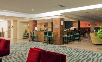 a bar area in a hotel lobby , with several chairs and tables placed around it at Copthorne Hotel Wellington, Oriental Bay