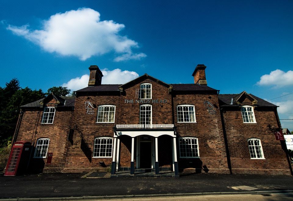 a brick building with a large white door and a blue sky in the background at The Nags Head