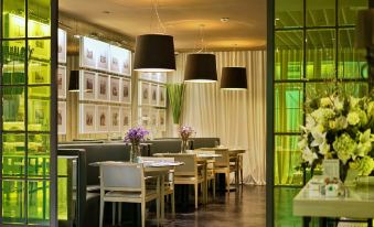 The restaurant is illuminated by green lighting on the windows, and it features white chairs and tables at Jinjiang Metropolo Classiq Jing'An Hotel