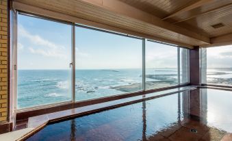 a long , rectangular swimming pool with a wooden floor and large windows overlooking the ocean at OARAI HOTEL