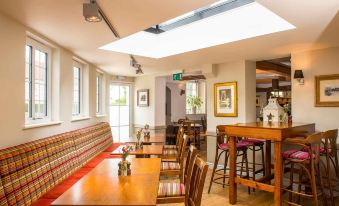 a cozy restaurant with wooden tables and chairs , a bar area , and a skylight above at The Lamb at Angmering