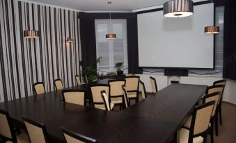 a conference room with a large table surrounded by chairs and a projector screen at the front at Filip
