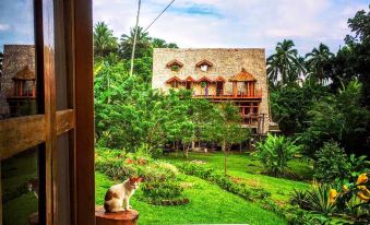 a large house with a balcony overlooking a lush green garden , creating a serene and tranquil atmosphere at Volcano House