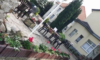 an outdoor dining area with several tables and chairs , surrounded by flowers and a building in the background at Hotel Waldhaus