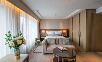 A spacious room is furnished with a bed, couch, and table in the center, resembling an oriental style at IFC Residence