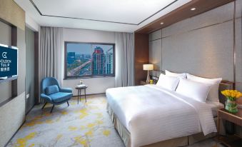 There is a bedroom with large windows, a bed, and a chair in the middle of the room next to it at Golden Tulip Shanghai