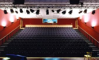 a large auditorium with rows of seats and a stage with multiple microphones , including one with a screen at Crowne Plaza Dublin - Blanchardstown