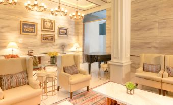 a modern living room with a piano in the center , surrounded by various chairs and couches at The Monarch Hotel