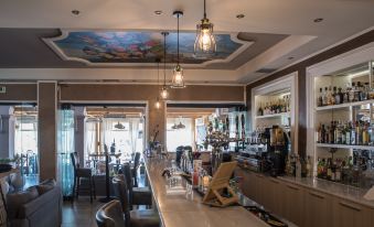 a modern bar with a large counter , multiple chairs , and pendant lights , as well as a dining area with tables and chairs at Dali