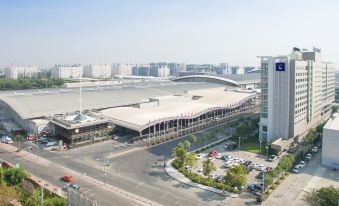 aerial view of an airport terminal building with cars parked in front of it , surrounded by buildings and a river at Novotel Bangkok Impact